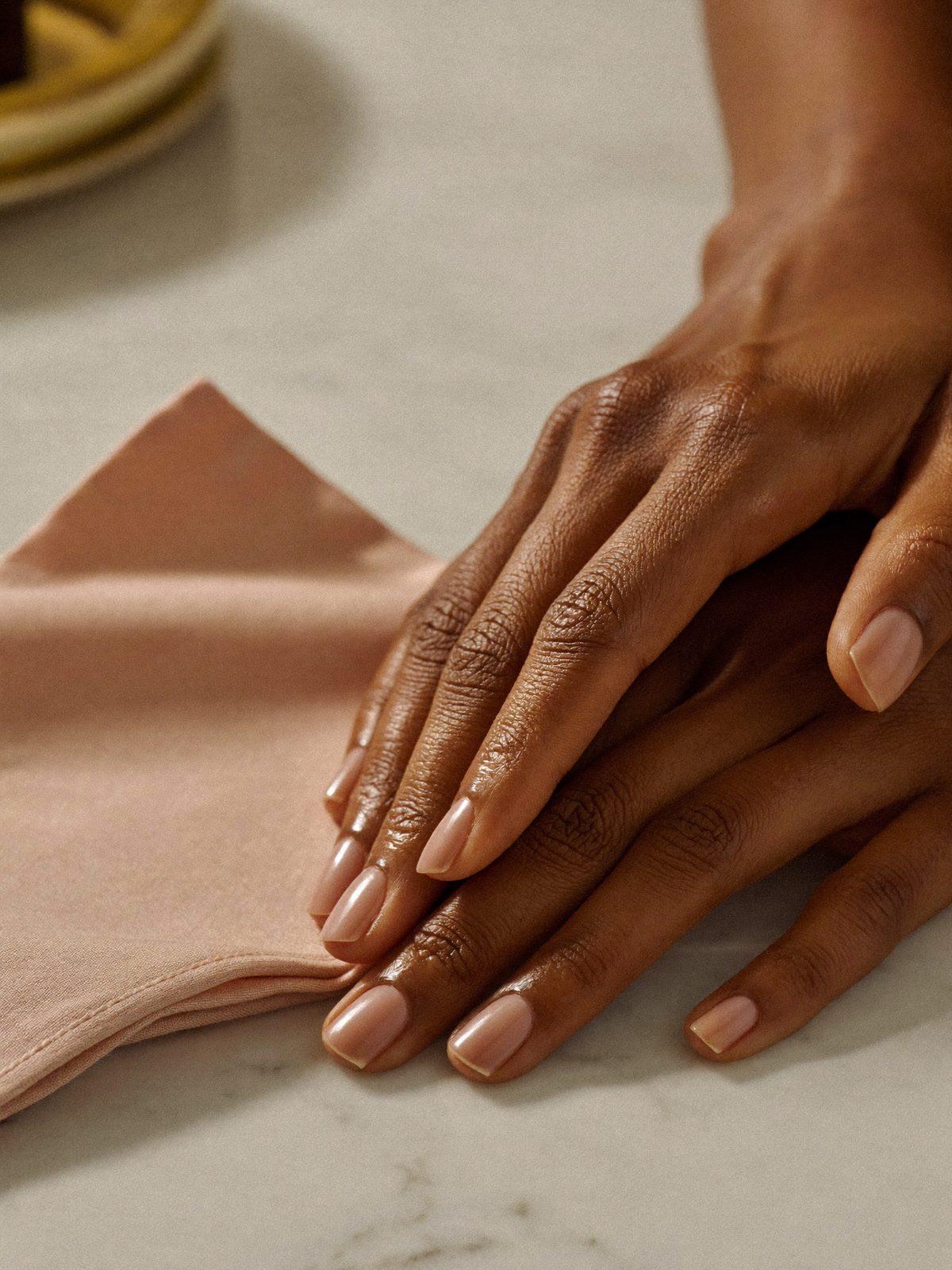 Manicured hands resting on a marble surface